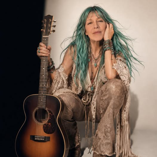 Aria Lightness seated with her guitar