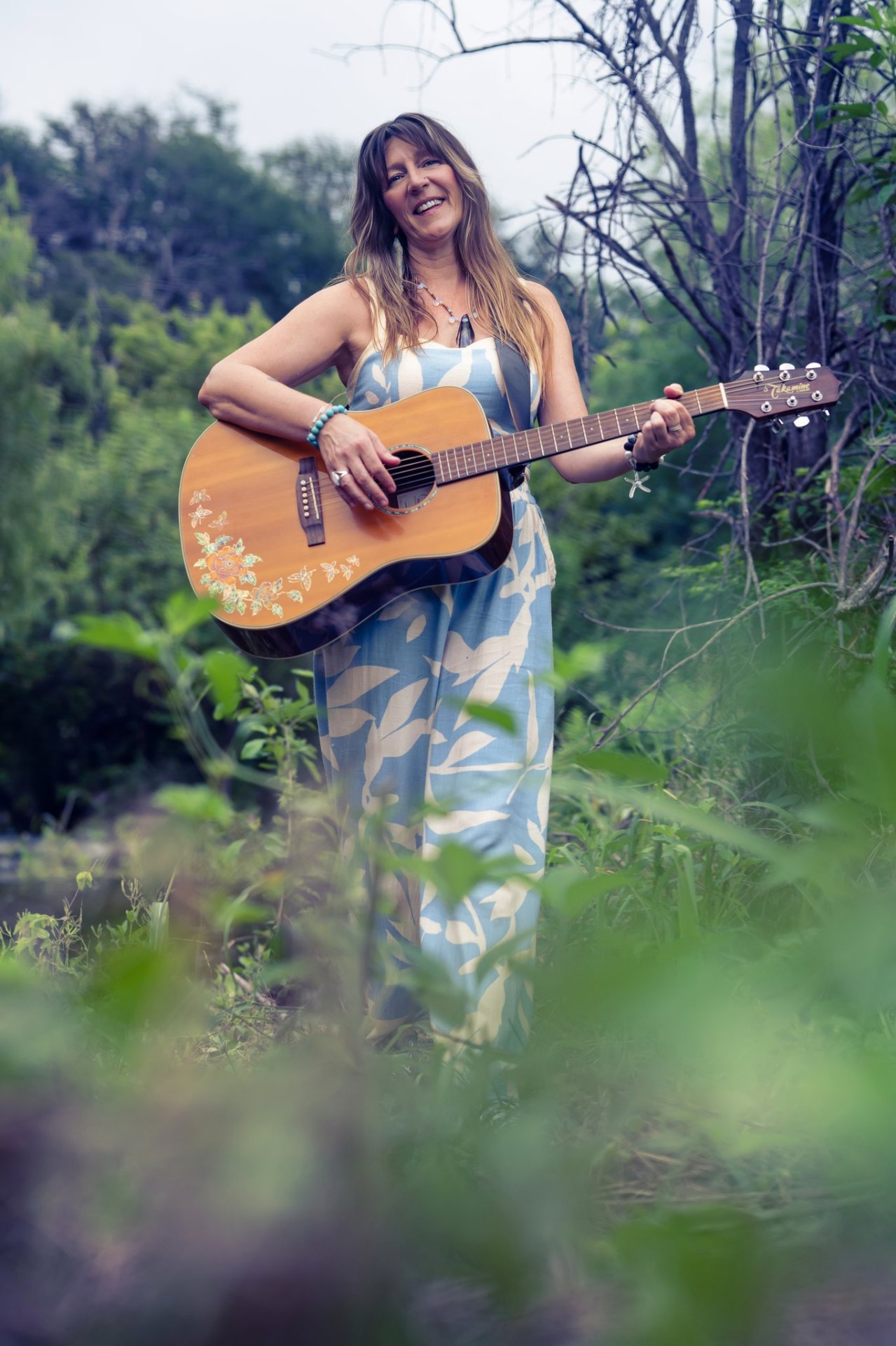Heidi Little standing outdoors with her acoustic guitar